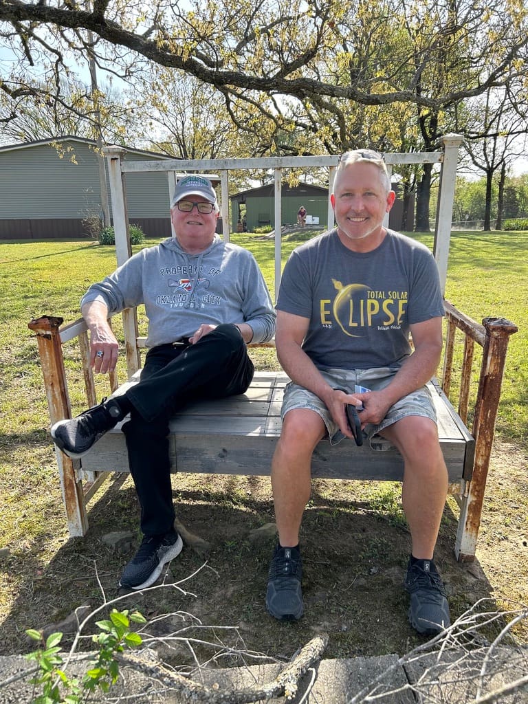 Two family members relaxing on the bench by the pond at Panorama Ranch.